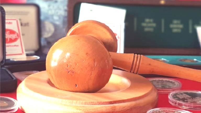 Bild: Schreibtisch beispielsweise eines Gerichtsvollziehers mit einem Gerichtshammer, Gesetzestext und Geldstücken