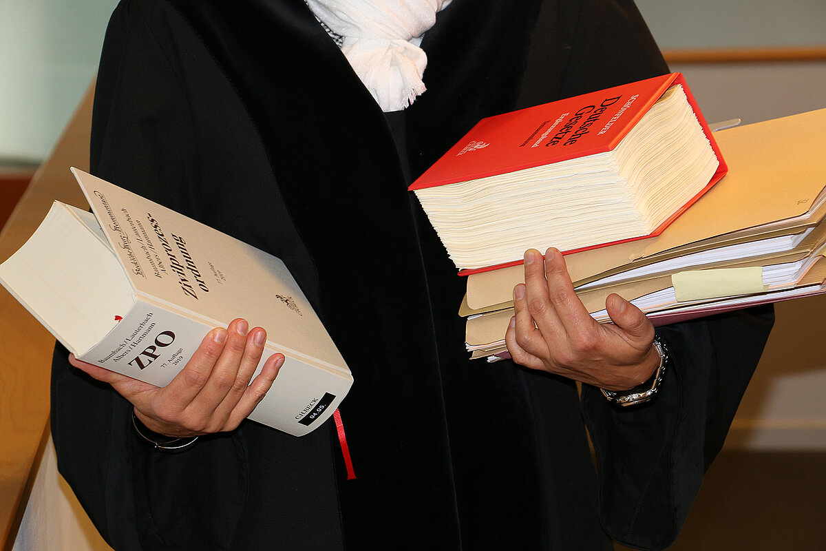Richterin in Robe mit einer Akte und Gesetzestexten