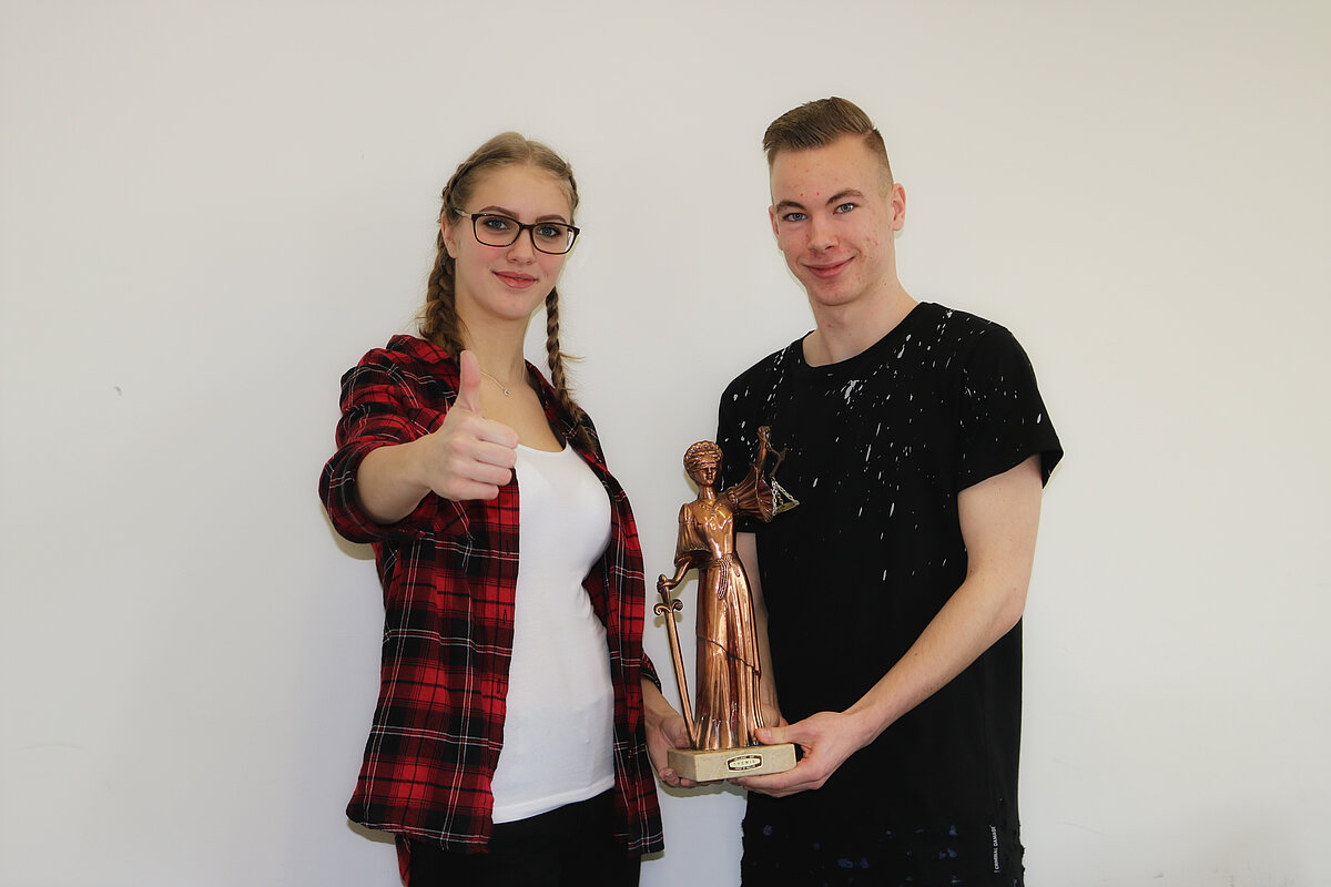 Bild: Zwei motivierende junge Menschen mit einer Justitia Bild: Zwei motivierende junge Menschen mit einer Justitia