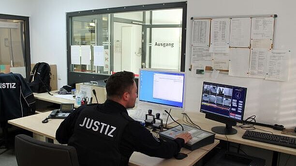 Bild: Justizwachtmeister während seiner Tätigkeit im Eingangs-/Auskunftsbereich.